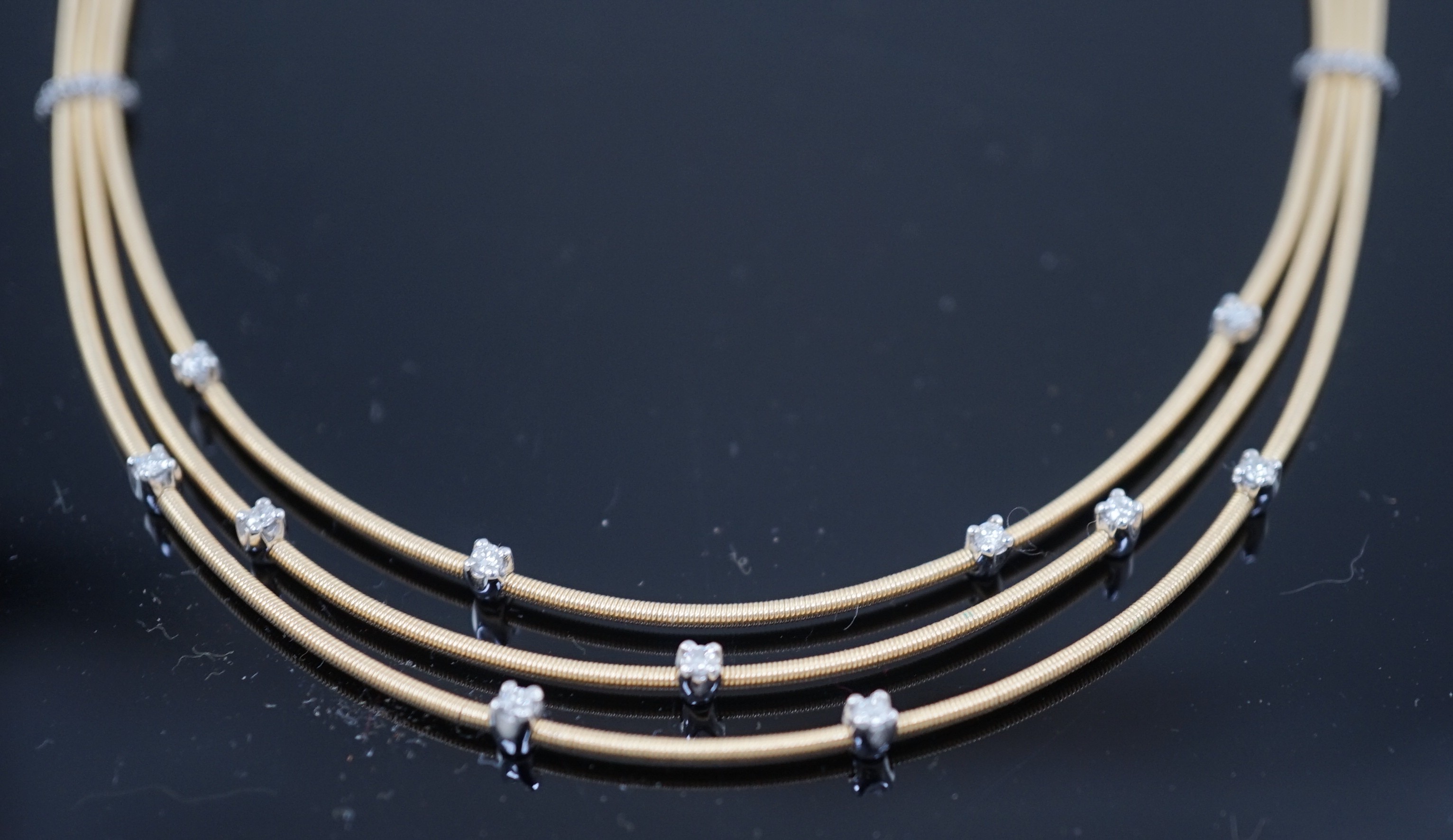 A modern Italian Marco Bicego 18ct gold and eleven stone diamond chip set triple strand necklace